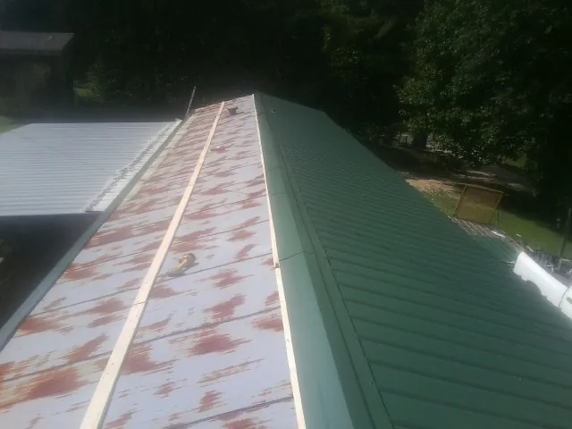 Old rusted panels beside newly installed green metal roofing — Wind Damage Roof Repair by Roofing Brothers in Blaine