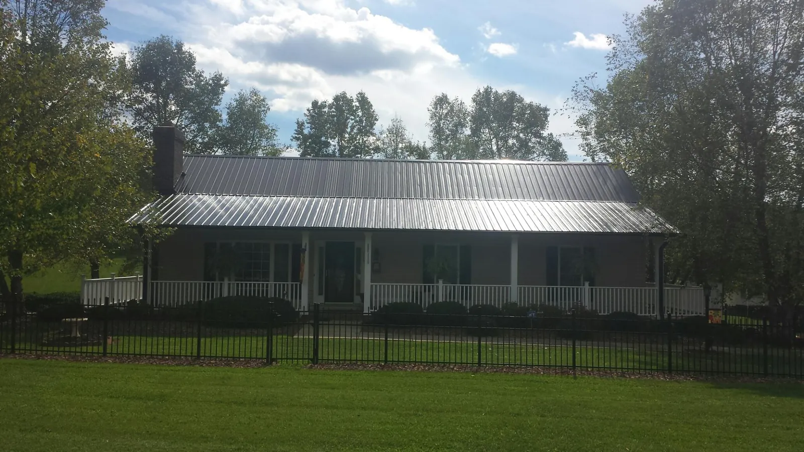 Gray metal roof on a brick ranch with a full width front porch — Gutter Guard Installation work by our crew in Blaine