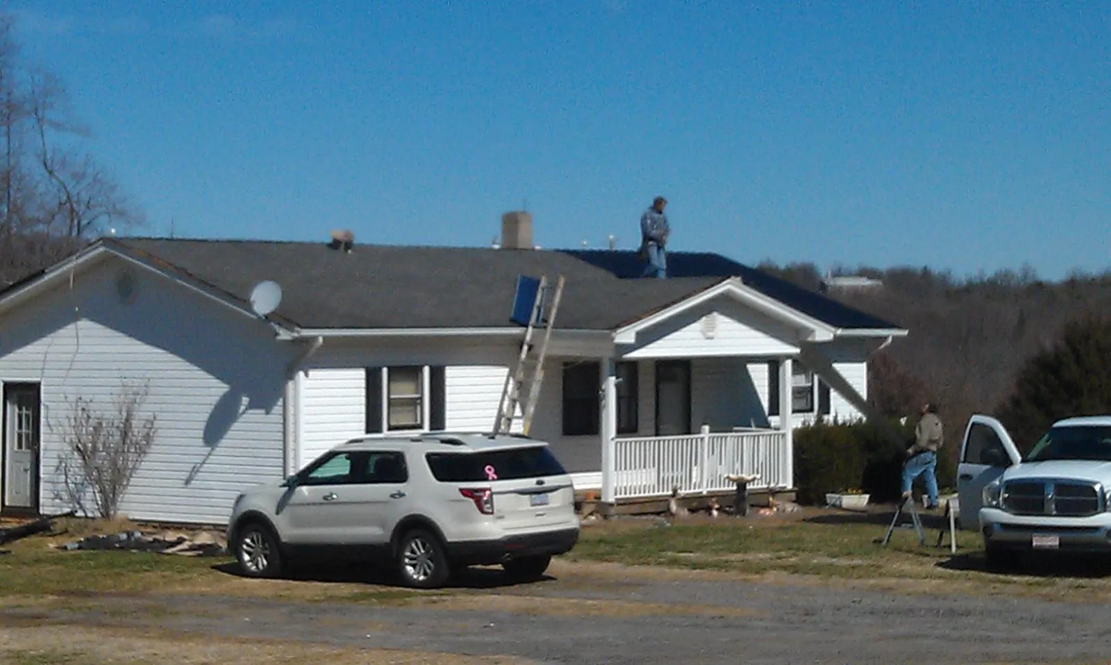 Roofers stripping shingles from a white ranch house roof in Blaine