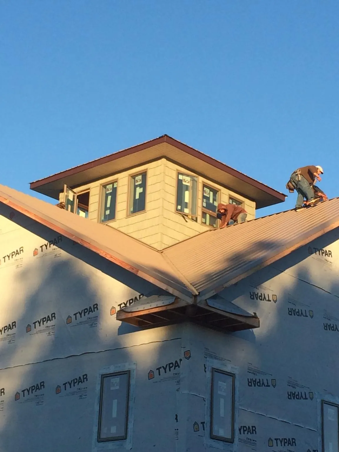 Roofers working around a rooftop cupola on a new metal roof at sunset — Roof Waterproofing in Blaine by Roofing Brothers